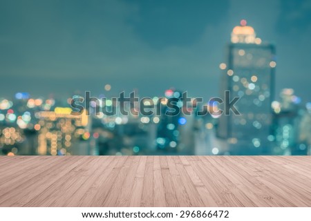 Wood floor in red brown color tone with blurred abstract background of Bangkok night lights downtown city view with colorful bokeh and flare in vintage style: Wooden table with blur background