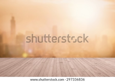 Aerial view of blurred abstract background of morning sunrise with flare from the kitchen balcony with wood floor in sepia brown color tone: Wooden table with blur cityscape view with gold light