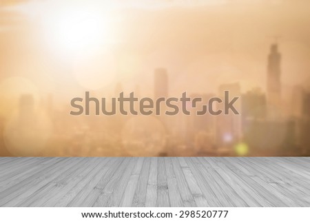 Aerial view of blurred abstract background of morning sunrise with flare from the kitchen balcony with wood floor in light sepia grey color tone: Wooden table with blur cityscape view with gold light