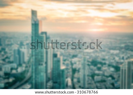 Blurred abstract background of rooftop view of downtown Bangkok urban skyline at sunset with bright sun flare in cool vintage color tone: Blurry twilight on city tour holiday travel vacation