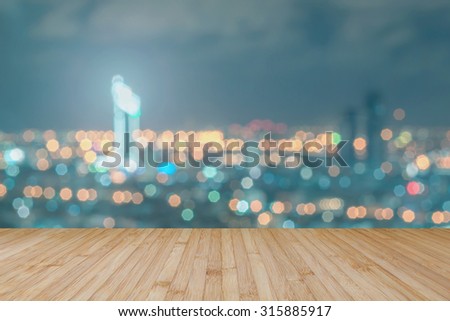 Wood floor in light yellow brown color tone with blurred abstract background of Bangkok city night lights rooftop view with bokeh lights: Wooden tabletop with blur background of urban cityscape