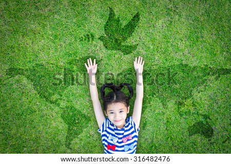 Happy Asian girl child raising hands with happiness lying peacefully w/ dove birds sign/ symbol & world map eco bio green grass: Peaceful mind kid in beautiful & clean love environment: csr concept