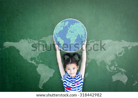 Happy Asian school girl kid child raising hands holding globe on green chalkboard with global world map background & empty copy space for adding texts: Child\'s education for world literacy day concept