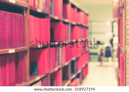 Vintage style color tone blurred abstract background of a view of an aisle of book shelves in library: Blurry interior perspective of old school day of study room with books stacks