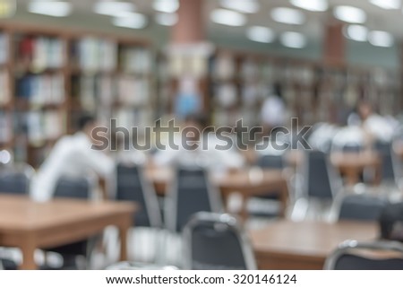 Blurred abstract background of a view school library with of aisles of book shelves and seats for reading: Blurry interior perspective of a study room with tables, chairs and stacks of books