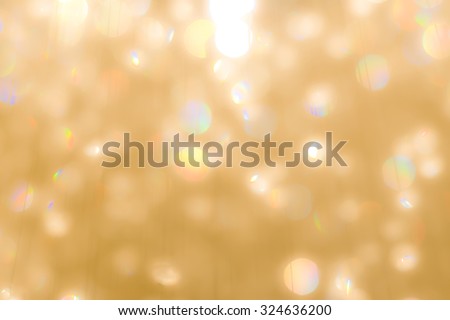 Blurred abstract background of reflective colorful rainbow bokeh of crystal mobile chandelier lamp on yellow gold color lighting in vintage colour tone: Sparkling lights of crystal glass reflection