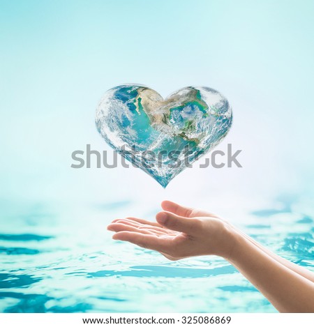 Blue green heart shape planet with turquoise cyan color wavy water background over beautiful woman human hands: World water environmental health concept: Elements of this image furnished by NASA