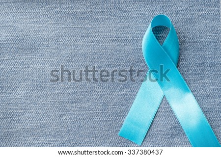 Light blue ribbon symbolic sign for prostate cancer awareness campaign and men\'s health in November and September on Jeans denim background: Shiny blue stin texture textile on Jeans backdrop