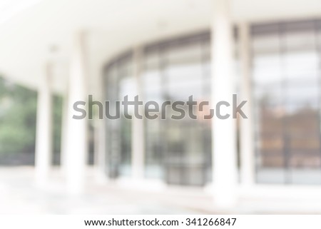 Blurred abstract background exterior view looking toward to empty office lobby and entrance doors and glass curtain wall with frame: Blurry perspective of reception hall to building interior entrance
