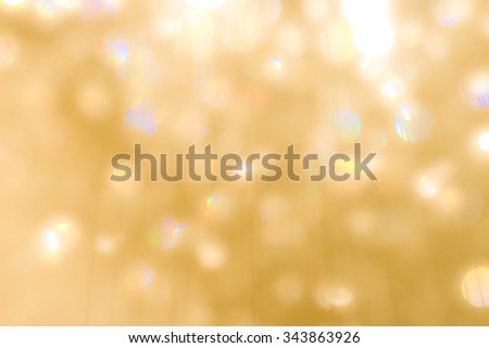 Blurred abstract background of reflective colorful rainbow bokeh of crystal mobile chandelier lamp on yellow gold color lighting in vintage colour tone: Sparkling lights of crystal glass reflection