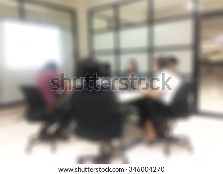 Blurred abstract background of business discussion people group or educational presentation in meeting room with projector slide screen in front of table, chair: Blurry view inside boardroom interior
