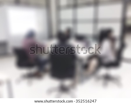 Blurred abstract background of business discussion people group or educational presentation in meeting room with projector slide screen in front of table, chair: Blurry view inside boardroom interior