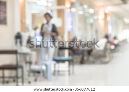 Blurred abstract background of hospital interior waiting hall/ corridor with patient on wheelchair in front of nurse station and OPD - out patient clinic department: Blurry view clinical indoor space