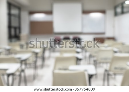 Blurred abstract background of empty seat row in school class  lecture room w/ white projector slide screen in front: Blurry interior view from back of the education classroom, no teacher nor student
