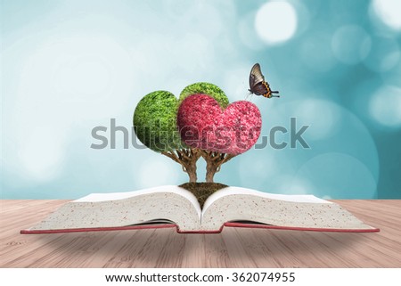 Perfect heart shape tree couple w/ beautiful butterfly growing on good soil planting on story book on wooden table w/ blurred natural background cool color vintage style bokeh: Happy Valentine\'s day