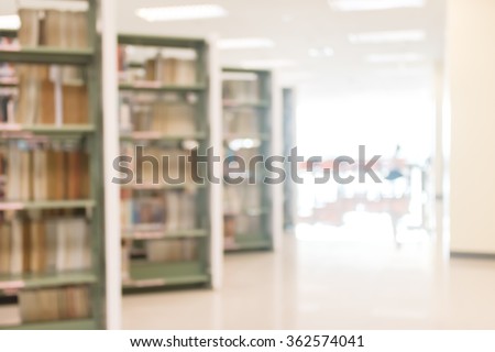 Blurred abstract background view of university student girl in aisle of book shelves in school library: Blurry interior perspective indoor study room with tables, chairs, seats & stacks of books