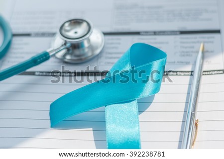 Light blue color ribbon awareness symbolic logo concept for prostate cancer awareness on empty patients health record paper note form with doctor stethoscope & pen for writing on working table/ desk