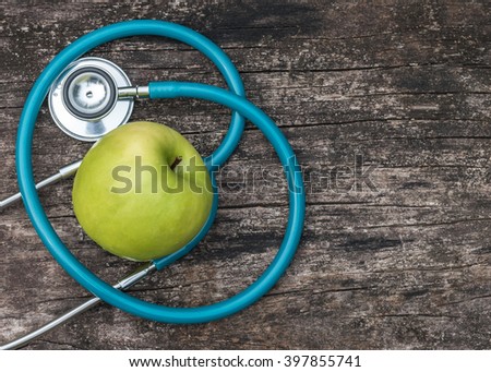 Green fresh organic natural nutrient apple with doctor\'s stethoscope heart shape on grunge old aged wood background: World health day WHD April 7 symbolic conceptual design idea for healthy food