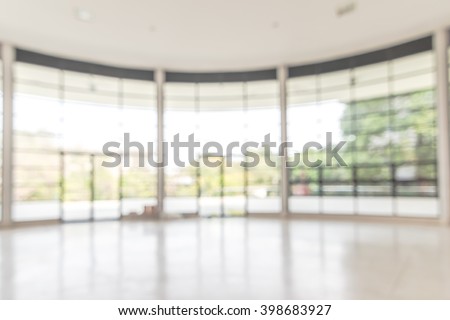 Blurred abstract background interior view looking out toward to empty office lobby and entrance doors and glass curtain wall with frame: Blurry perspective of reception hall to building entrance