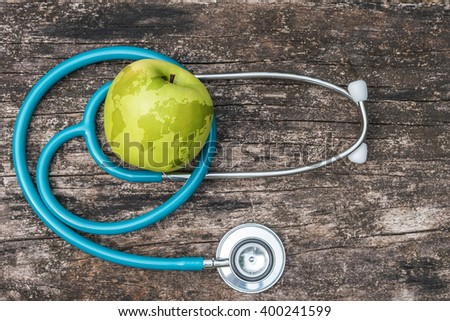 Map on healthy fruit food green fresh organic natural nutrient apple w/ doctor\'s stethoscope heart shape grunge old aged wood background: World health day WHD April 7 symbolic conceptual design idea