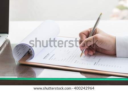 Person\'s hand with ballpoint pen writing on blank application form paper: Fill in empty document template applying for a job, finance, loan, mortgage or a claim for health, business insurance concept