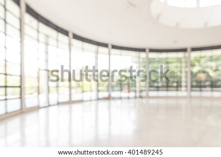 Blurred abstract background interior view looking out toward to empty office lobby and entrance doors and glass curtain wall with frame: Blurry perspective of reception hall to building entrance