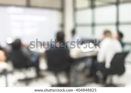 Blurred abstract background of business discussion people group or educational presentation in meeting room with projector slide screen in front of table, chair: Blurry view inside office interior