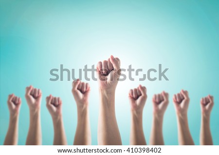 Human fist gesture among blur arm group on vintage blue sky background: Female woman clenched hand raising up showing power strong bunch of five: Women rights strengthening empowering conceptual idea