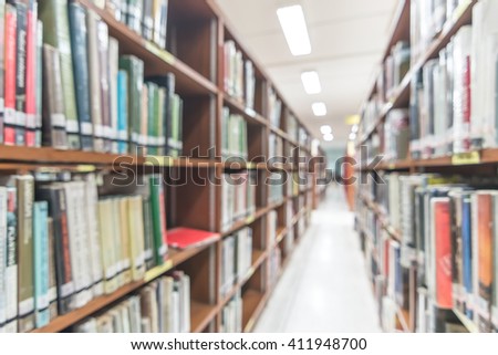 Blurred abstract background view of university student girl behind aisle of book shelves in school library: Blurry interior perspective indoor study room with tables, chairs, seats & stacks of books