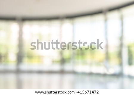 Blurred abstract background interior looking out toward empty office lobby and entrance doors/ transparent glass curtain wall frame: Blurry perspective view reception hall to public building entrance