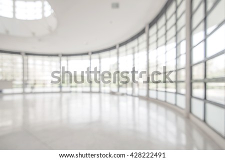 Blurred abstract background exterior view looking out toward to empty office lobby and entrance doors and glass curtain wall with frame: Blurry perspective of reception hall to building entry/ exit