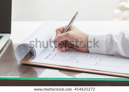 Person\'s hand with ballpoint pen writing on blank application form paper: Fill in empty document template applying for a job concept