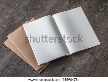 Blank open book, catalog, magazines, brochure, note template w/ paper texture on dark grey color wood table/ wooden floor background: Empty textured note book pages on timber backdrop for adding text