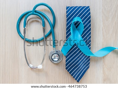 Light blue ribbon symbolic sign for prostate cancer awareness campaign and men\'s health in November and September on necktie, doctor\'s stethoscope on wood table: Shiny blue satin on wooden backdrop