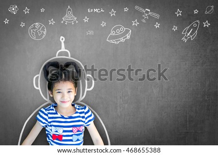 Happy little asian girl kid in astronaut suit doodle chalk board drawing & universe space out of earth planet on school black chalkboard background: Creative innovation educational conceptual idea