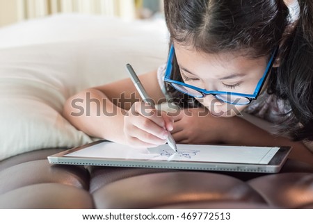 Happy Asian girl kid enjoy using pen on tablet smart technology gadget pc pad device drawing freehand doodle leisure art on fun free time: Little school child draw cartoon  innovative pro touchscreen