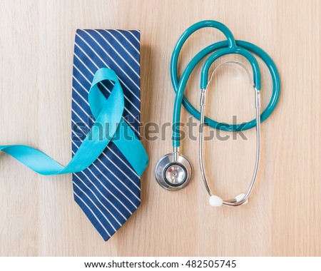Light blue ribbon symbolic sign for prostate cancer awareness campaign and men\'s health in November and September on necktie, doctor\'s stethoscope on wood table: Shiny blue satin on wooden backdrop