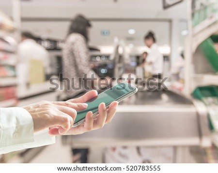 Business person hand using cellphone (clipping path) blur abstract background supermarket cashier counter: Woman user typing mobile phone apps touchscreen shopping ordering buying purchase payment