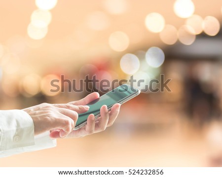 Business person hand using cellphone (clipping path) blur abstract background shopping mall department store: Woman user typing mobile phone touch screen telecommunication buying purchase payment