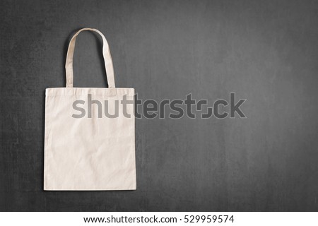 Fabric cloth cream shopping bag on grunge slate blackboard background: Reusable eco friendly white brown tote made of natural cotton material: Reduce reuse recycle environmental concept campaign