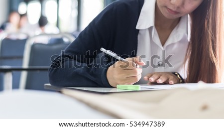 School student's hand holding pen writing taking exam, or young asian adult college people study in class room doing education examination in university classroom testing learning outcome score result