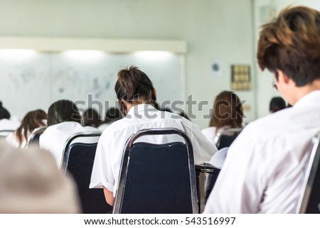 University students women/ men\'s back in uniform attending examination in classroom educational institute: Rear perspective view full room of school college people having exams in class room seat row