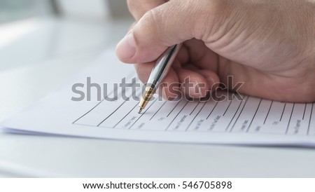 Applicant\'s hand holding ballpoint pen writing on empty application form paper: Business person fill in blank document sheet applying job position, mortgage loan, registering registration information