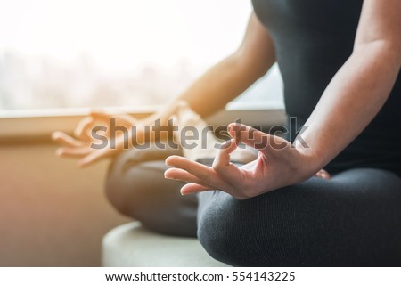 Young woman girl relax sitting in yoga lotus pose position Padmasana in peaceful home indoor interior space next to window: Meditation in peace quiet gym house room passive exercise sport activity