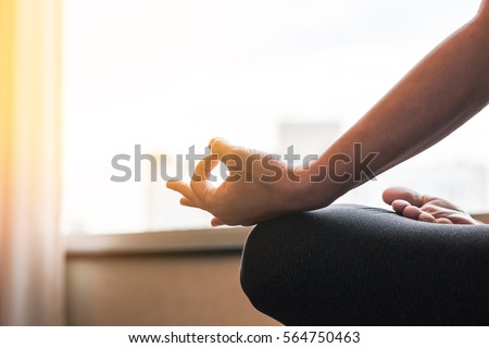 Young woman girl relax sitting in yoga lotus pose position Padmasana in peaceful home indoor interior space next to window: Meditation in peace quiet gym house room passive exercise sports activity