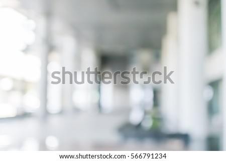 Blurred abstract background interior view looking out toward to empty hotel/ office lobby entrance doors and glass curtain wall with frame: Blurry perspective of reception hall to building entry/ exit