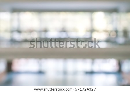 Blurred abstract background interior view looking out toward to empty office lobby, corridor walk way and glass curtain wall with frame and light: Blur view of reception hall to building window facade