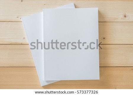 Blank A4 size book cover template with page in front side lay flat on clean white cream surface wood background: Empty paperback magazine catalog note book paper texture mockup on wood table backdrop