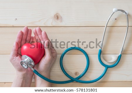 Red single heart love shape hand exercise ball MD medical doctor physician\'s stethoscope clean white wood background: Hospital life insurance healthcare concept: World heart health day conceptual idea