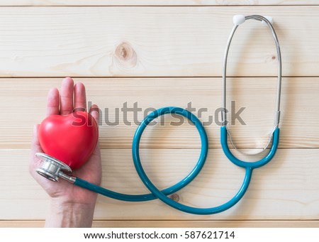 Red single heart love shape hand exercise ball MD medical doctor physician\'s stethoscope clean white wood background: Hospital life insurance healthcare concept: World heart health day conceptual idea
